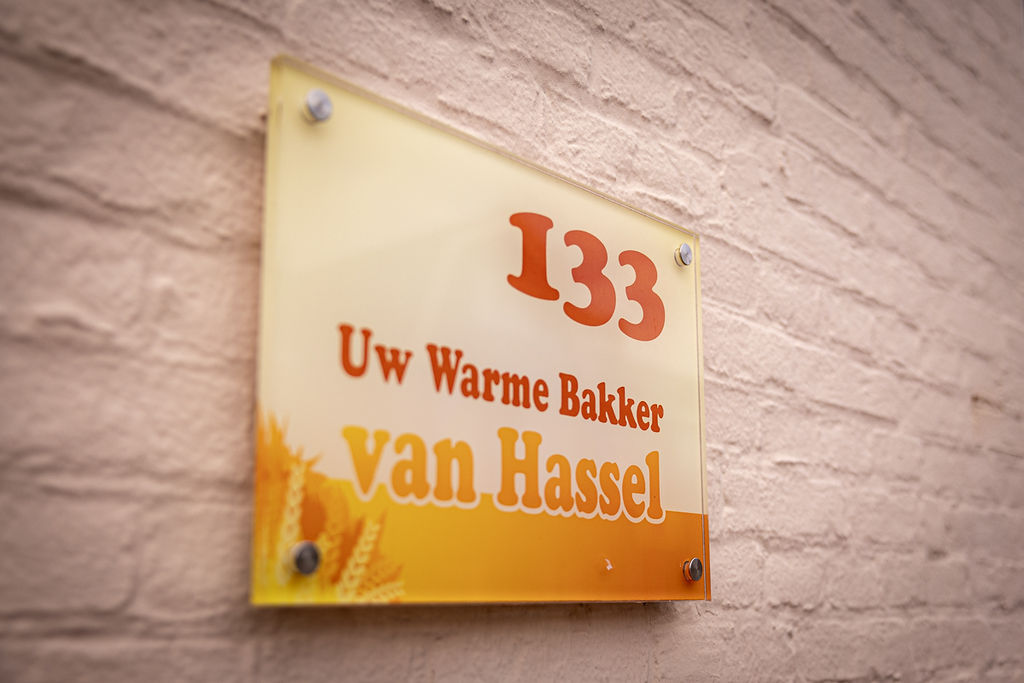 Het naambord 'Uw warme bakker van Hassel 133' aan de gevel